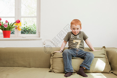 坐在沙发垫上的小男孩图片