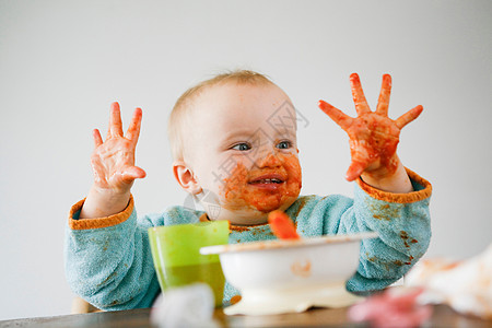 孩子吃东西满手是番茄酱的婴儿背景