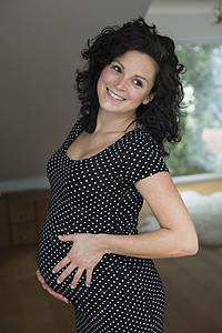 微笑的怀孕中年妇女触摸肚子的照片图片