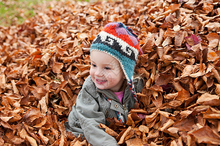 在树叶堆里玩耍的女孩图片