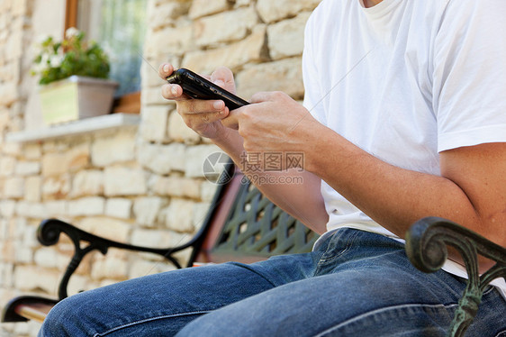 在长凳上用手机的男人图片