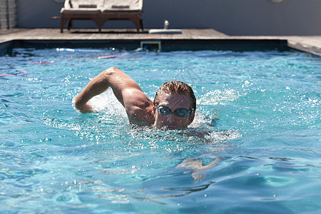 戴护目镜的人在游泳池里游泳背景图片