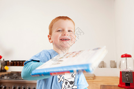 在厨房拿书的微笑男孩图片
