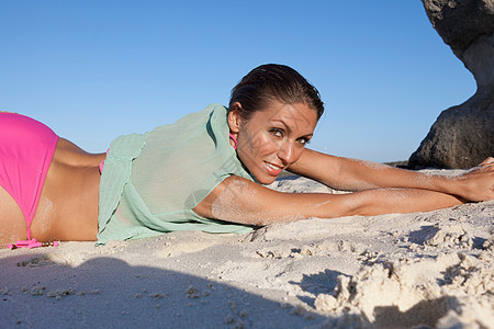 穿比基尼的女人躺在海滩上图片