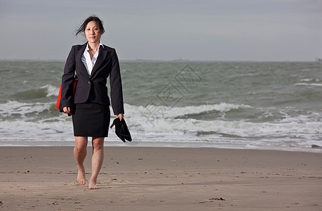 女商人赤脚在海滩上行走图片