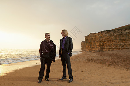 日落时分两个人站在海滩上图片