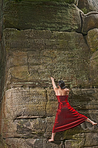 身着红色连衣裙的女子自由攀爬砂岩烟囱岩面高清图片