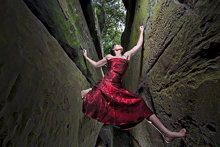 身着红色连衣裙的女子自由攀爬砂岩烟囱岩石缝隙图片
