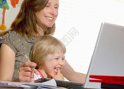 坐在母亲膝上看电脑的女孩图片