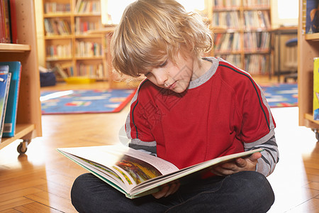 阅读小孩男孩在地板上看书背景