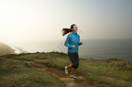 一位年轻女子沿着悬崖小道慢跑图片
