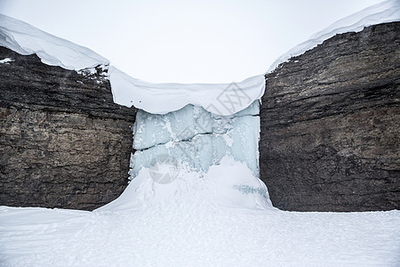 挪威斯瓦尔巴岩石间的冰冻瀑布景观图片