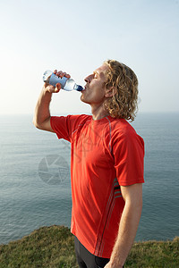 一个年轻的男运动员从瓶子里喝水图片