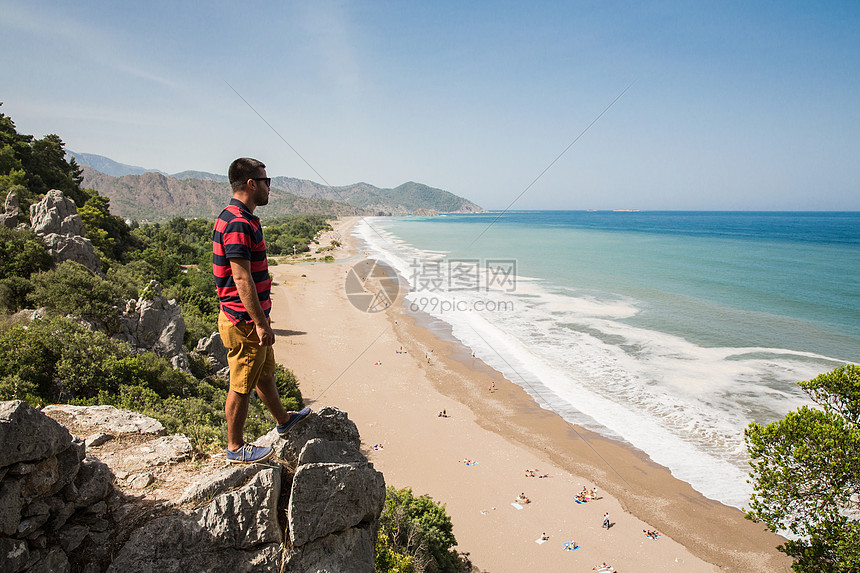站在悬崖上的人俯瞰土耳其莱西恩路奥林匹斯海滩图片
