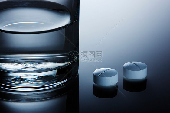 桌面上的药丸和水杯特写图片