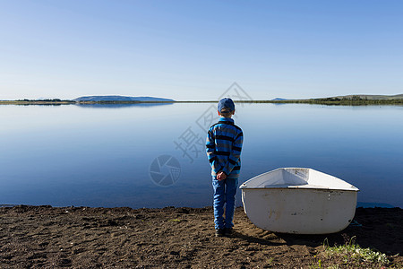 站在湖边划艇旁边的小男孩图片