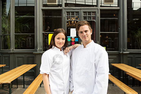 穿着厨师制服的夫妇站在餐厅外形象图片