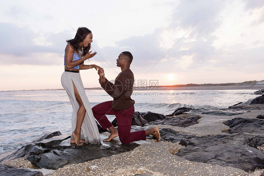 ‘~中年男子跪在海边的岩石上向年轻女子求婚  ~’ 的图片