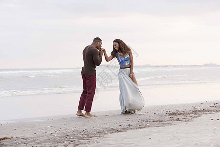 海滩上的情侣，男人亲吻女人的手图片