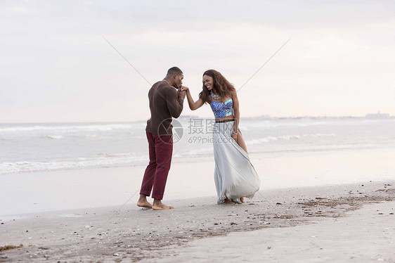 海滩上的情侣，男人亲吻女人的手图片