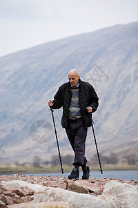 老人拄着手杖行走背景图片