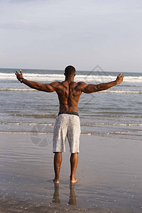 站在海滩上的中年男子双臂张开展示肌肉图片