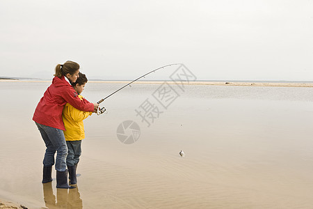 母亲教儿子在海滩钓鱼图片