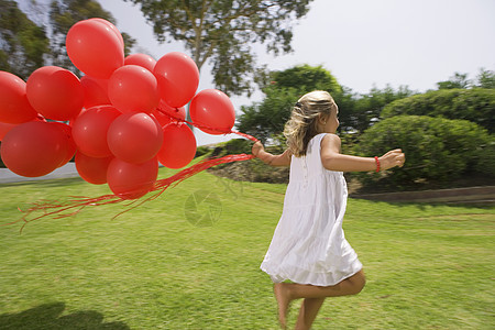 带着红色气球奔跑的年轻女孩图片