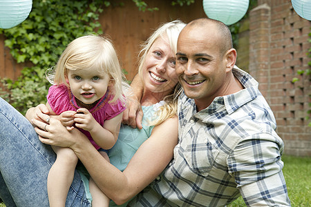 一对幸福的夫妇和幼小的女儿坐在花园里的照片图片