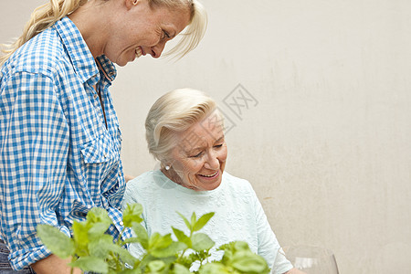 老太太和孙女在花园的桌子上聊天图片