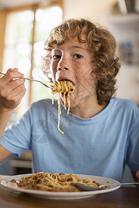 十几岁的男孩在餐桌上吃意大利面图片