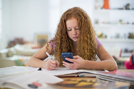 少女写笔记和使用智能手机背景图片