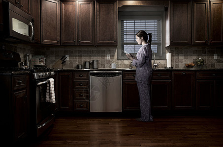 夜晚女人在厨房使用平板电脑图片