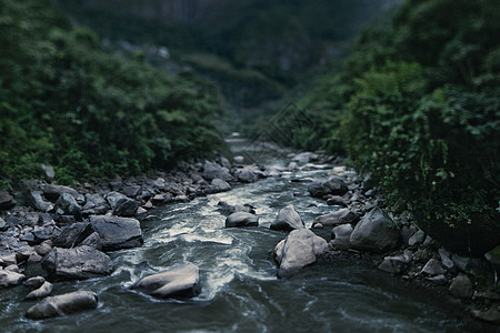 秘鲁圣谷Ollantaytambo岩石和树叶流淌的溪流景观背景图片