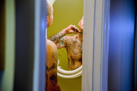 有纹身的男人刮胡子，从浴室门往外看图片