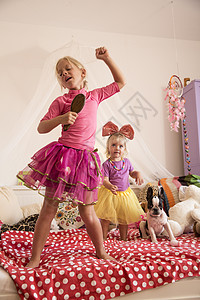 女孩和妹妹在床上用麦克风跳舞唱歌背景图片