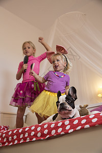 女孩和学步的妹妹在床上用跳舞唱歌图片