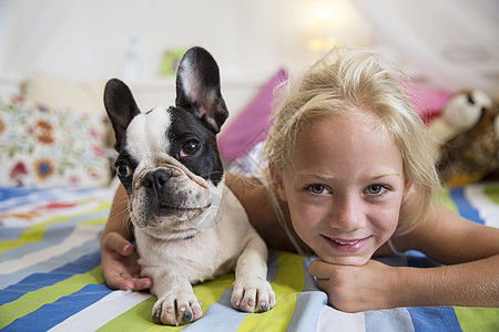躺在床上的女孩和可爱的狗的肖像图片