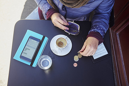 街边咖啡厅中年妇女数欧元硬币俯视图图片