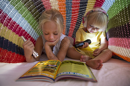女孩和她的妹妹使用手电筒看书图片
