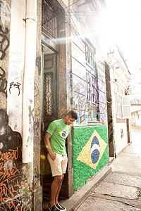 穿着巴西上衣的年轻人站在巴西国旗旁边的门口图片