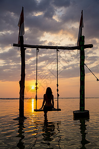印度尼西亚秋千上观看日落的女性游客剪影图片素材
