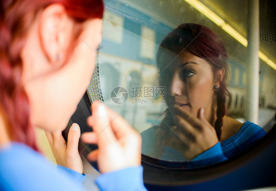 洗衣店里的年轻女人看着洗衣机里的倒影图片