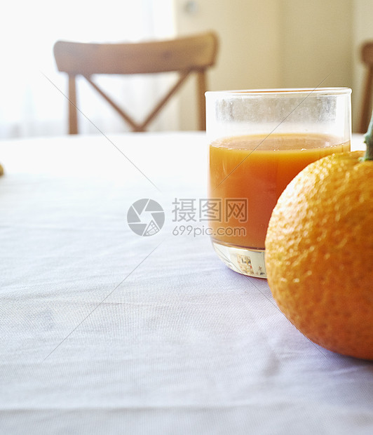 桌子上一个橙子和一杯橙汁的特写镜头图片
