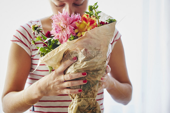 中年妇女在窗前闻着一束花图片