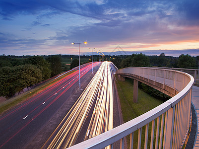 黄昏时人行桥和公路红绿灯小道的高视图图片