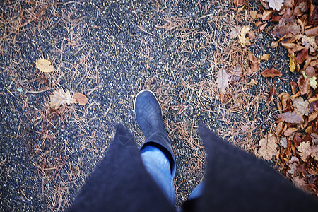 穿胶靴的女人在秋叶中漫步图片