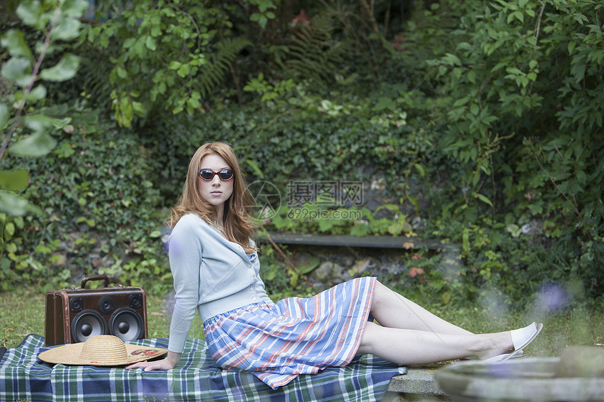 坐在花园里野餐毯上的女人图片