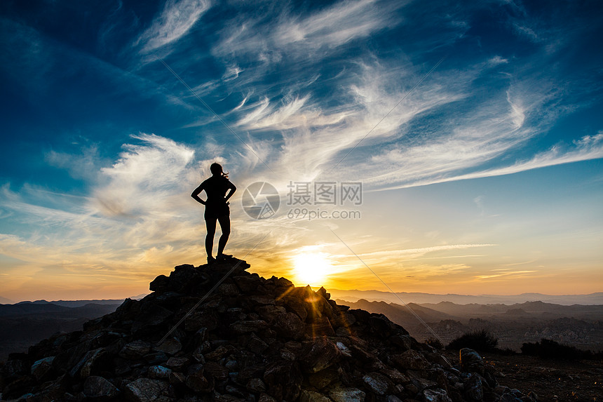 日落时分站在山顶眺望远方的妇女剪影图片