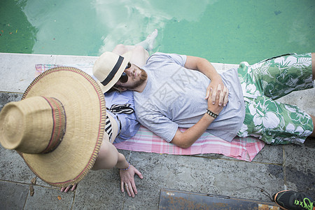 在泳池边的毯子上放松的情侣图片